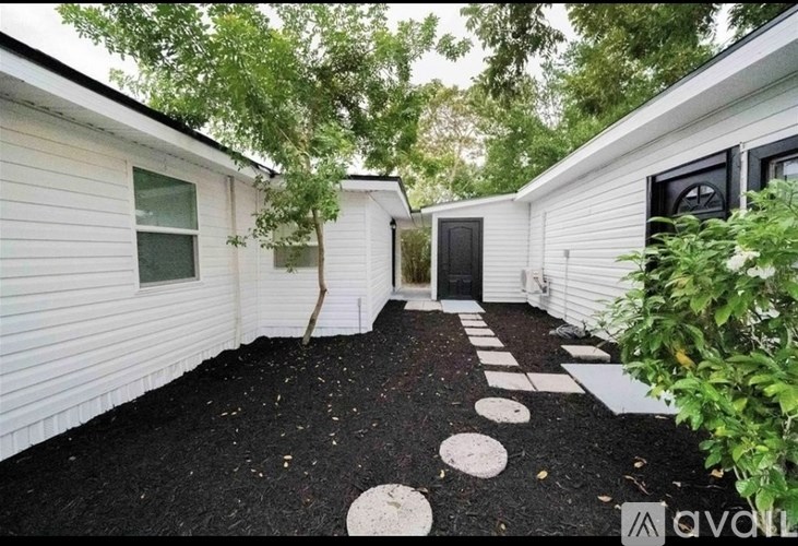 A backyard with a black mulch and white stepping stones.