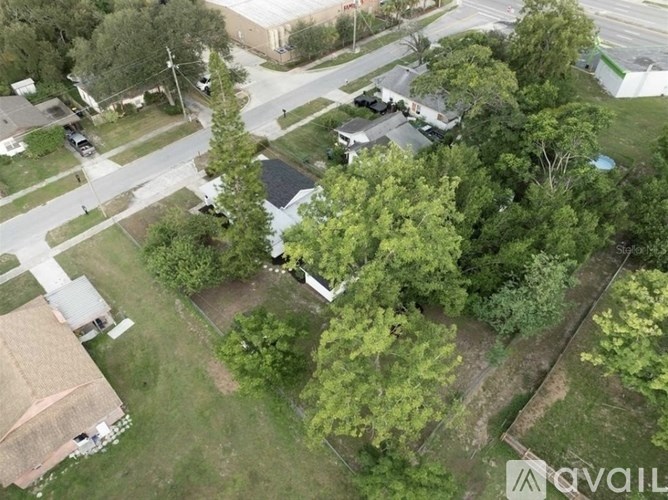 A bird's eye view of a residential area with houses, trees, and a road.