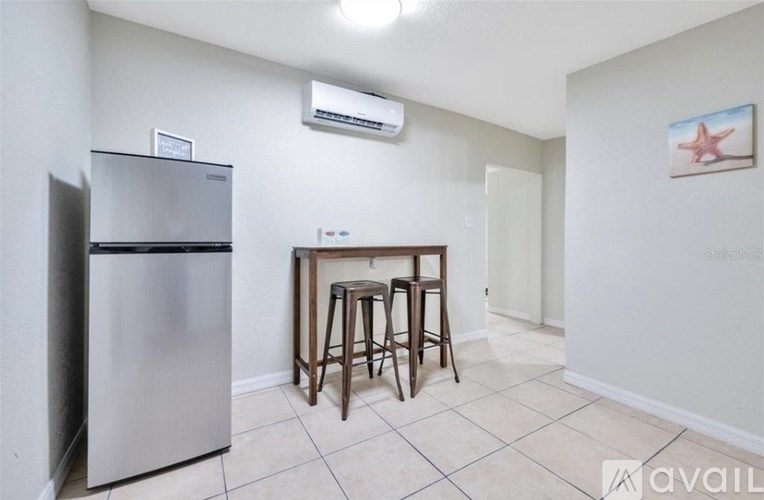 A kitchen area with a refrigerator, a table with two chairs, and a starfish decoration on the wall.