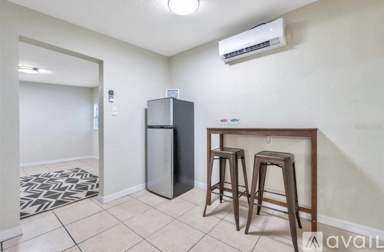 A kitchen area with a bar stool, a fridge, and a counter.