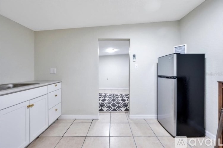 A kitchen with white cabinets and a black fridge.