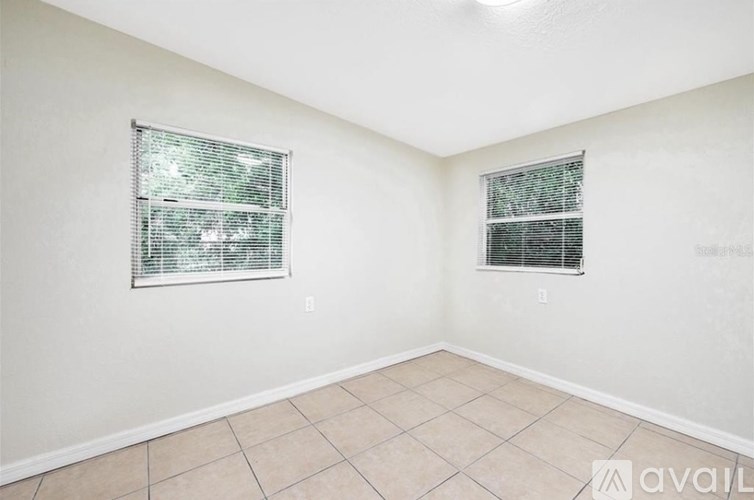 A room with two windows and tiled flooring.
