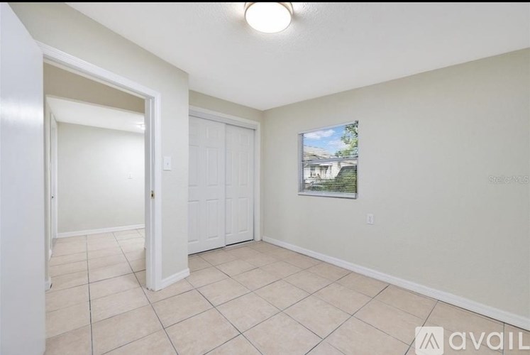A room with a white door and a window showing a house outside.