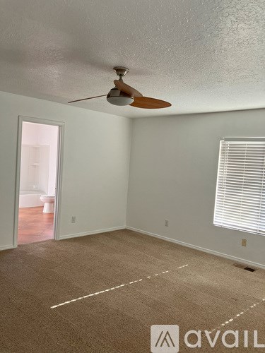 A room with a ceiling fan and a window with blinds.