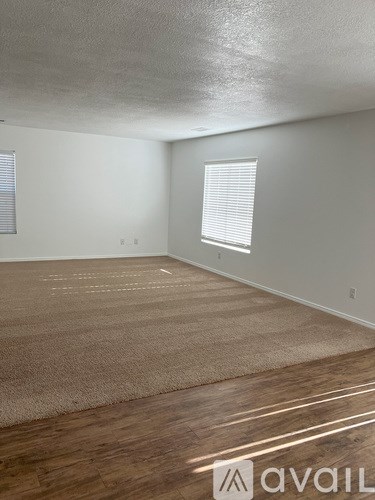 A room with a carpeted floor and a window with blinds.