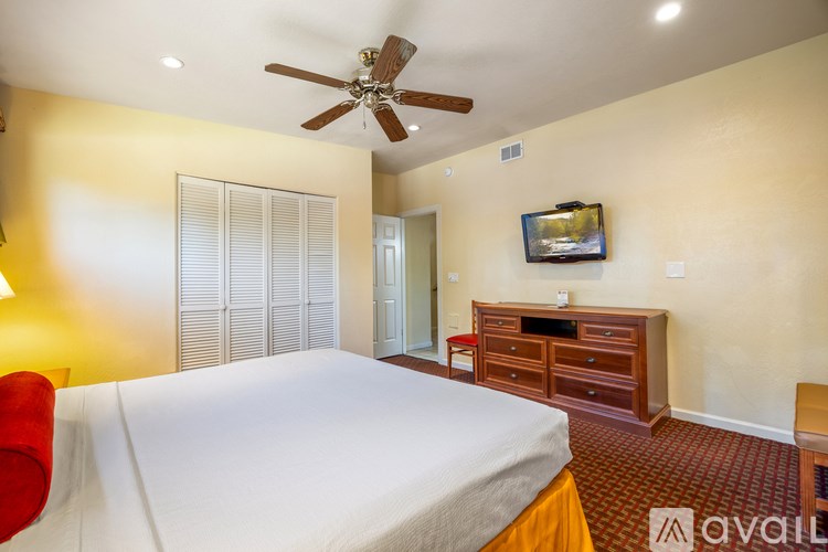 A bedroom with a bed, a TV, and a dresser.