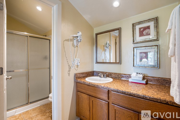 A bathroom with a sink, mirror, and a shower with a glass door.