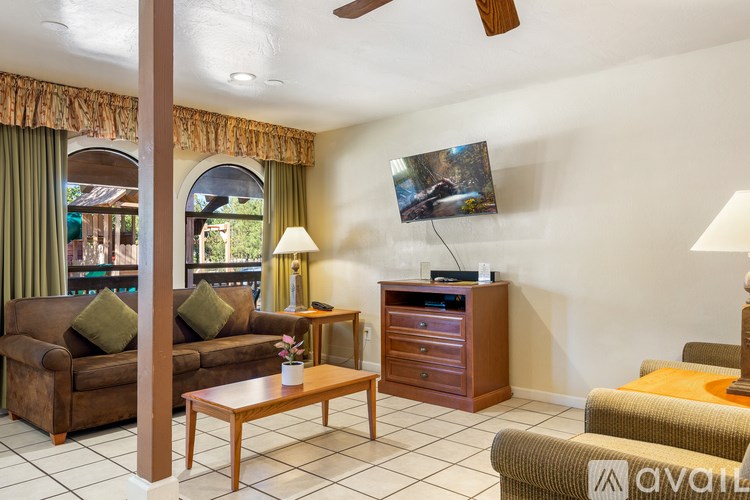 A living room with a brown couch, a wooden coffee table, and a flat screen TV mounted on the wall.