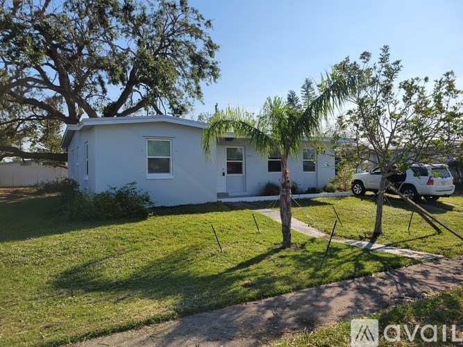 A white mobile home with a green lawn and trees in front.