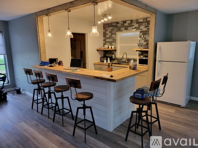 A kitchen with a bar area and four stools.