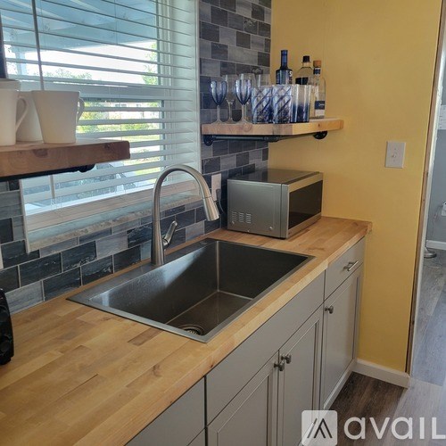 A kitchen with a wooden counter top and a stainless steel sink.