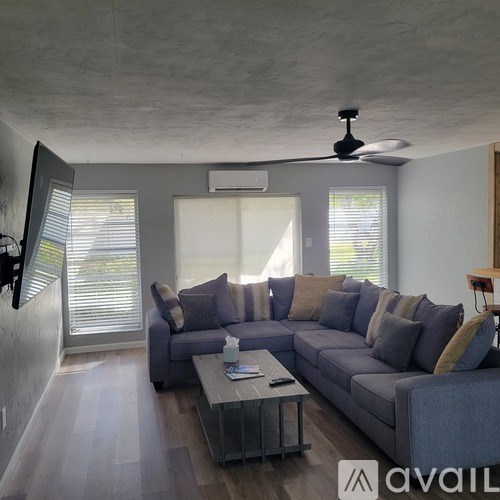 A living room with a grey couch and a ceiling fan.