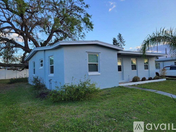 A blue house with a white roof and a tree in front.