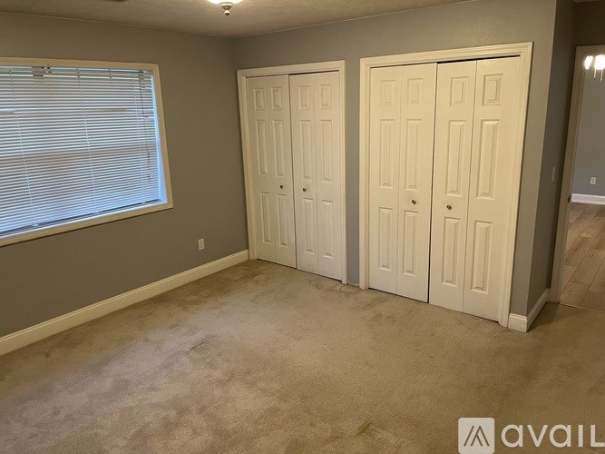 A room with two white doors and a window with blinds.