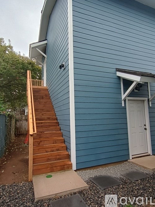 A blue house with a white door and a wooden staircase.