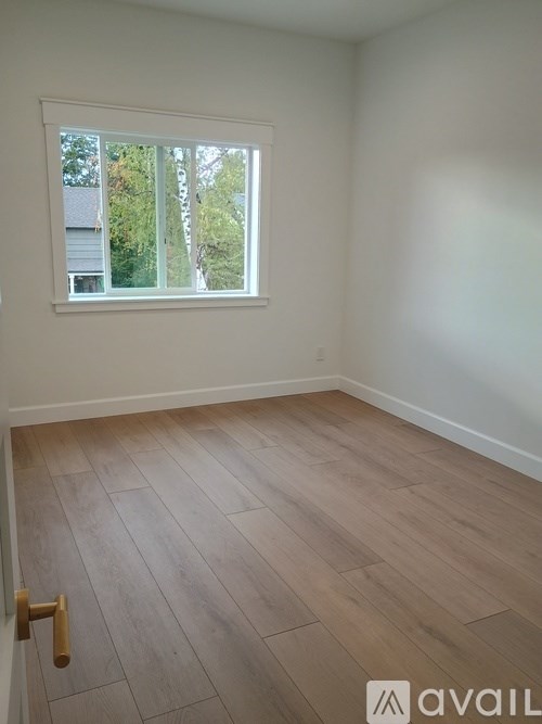 A room with a window and wooden flooring.
