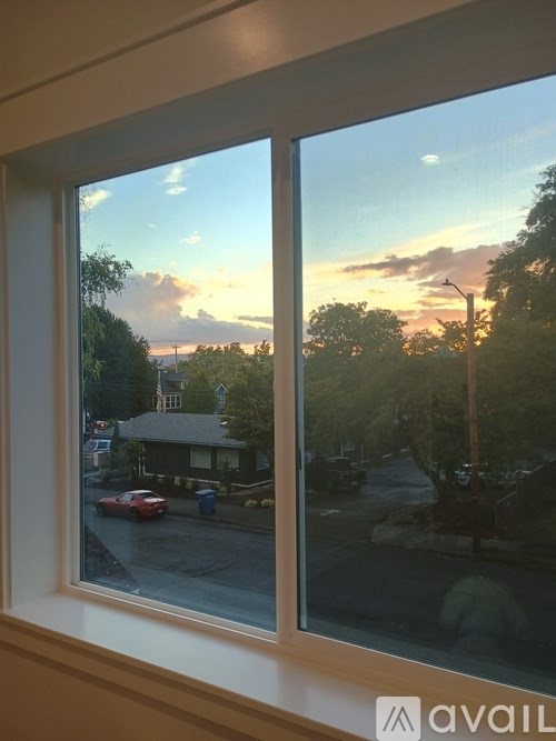 A view of a street through a window with a house and cars visible.