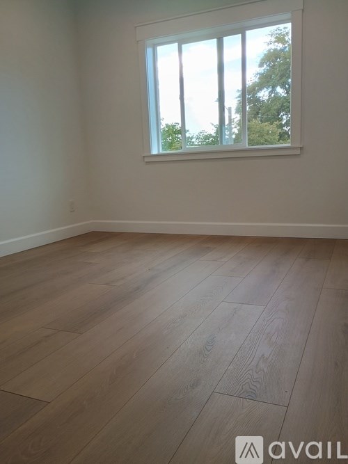 A room with wooden flooring and a window.