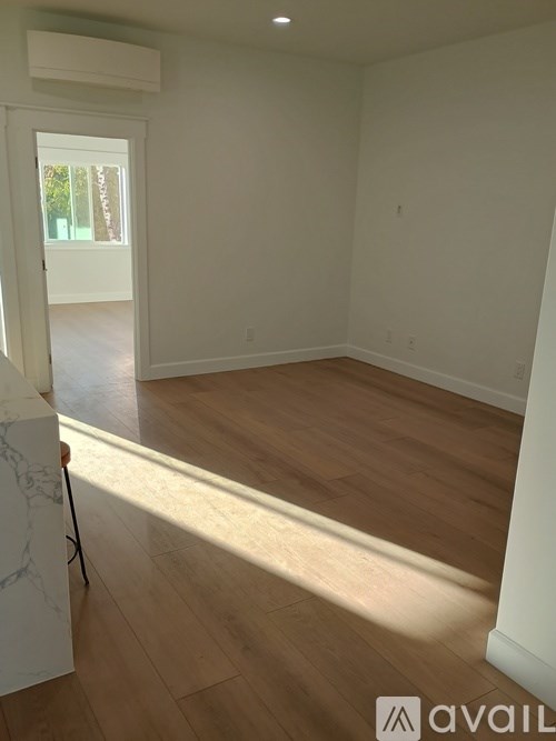 A room with wooden flooring and a doorway leading to another room.