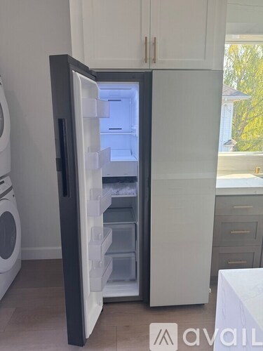A black fridge with the door open in a kitchen.