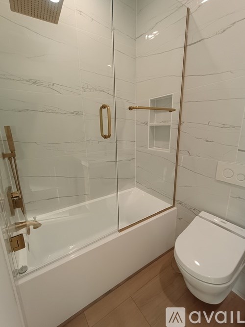 A white toilet sits next to a glass shower stall in a bathroom.