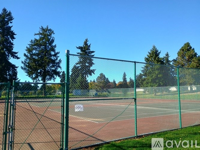 A tennis court is enclosed by a green fence.