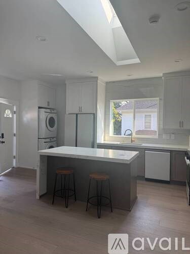 A kitchen with white cabinets and a central island with bar stools.