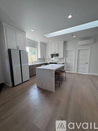 A kitchen with white cabinets and a marble island.
