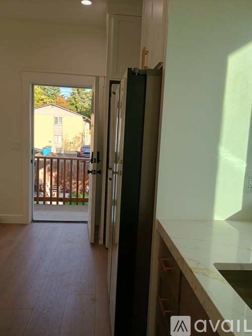 A kitchen with a refrigerator and a view of a backyard.