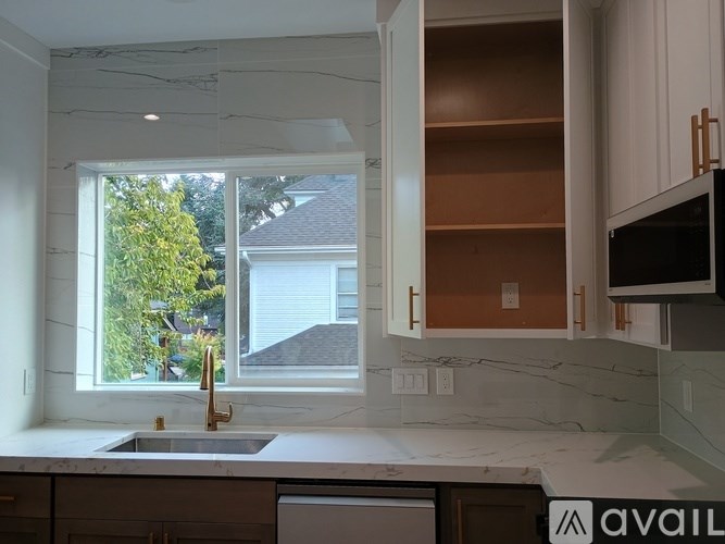 A kitchen with a sink, a window, and a microwave.
