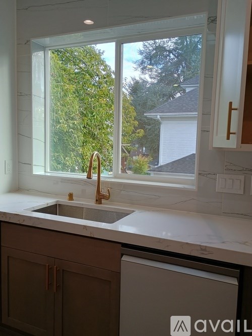 A kitchen with a window overlooking a tree.