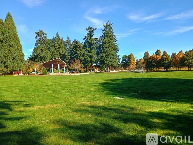 A grassy field with a pavilion and trees in the background.