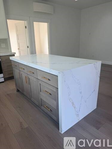 A white marble countertop with drawers underneath it in a room with wooden flooring.