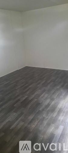 A room with wooden flooring and a white wall.