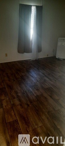 A room with wooden flooring and a window with curtains.