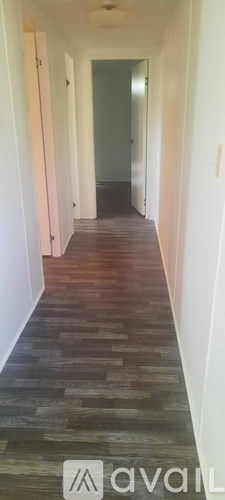 A long hallway with wooden floors and white walls.