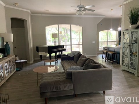 A living room with a piano, a couch, and a fan.
