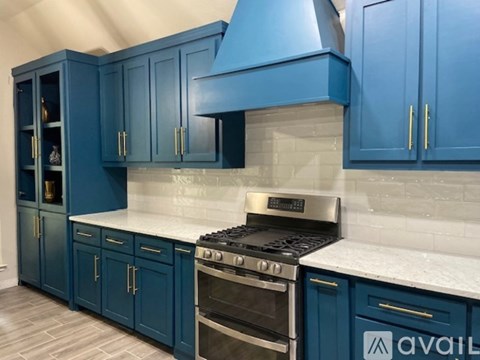 A kitchen with blue cabinets and a stove top oven.