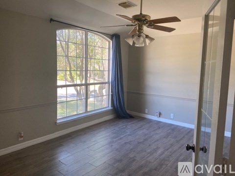 A room with a ceiling fan and a sliding glass door leading to a backyard.