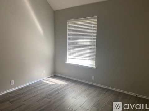 A room with wooden flooring and a window with blinds.