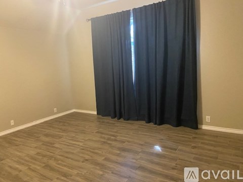 A room with a dark curtain and wooden flooring.