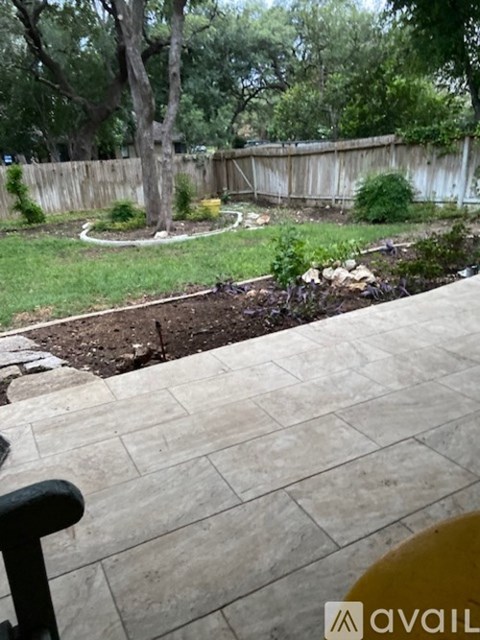 A backyard with a circular garden bed and a stone patio.