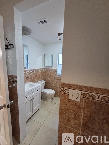 A bathroom with brown tiles and a white toilet.