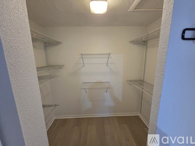 Empty walk-in closet with white walls and wooden floors.