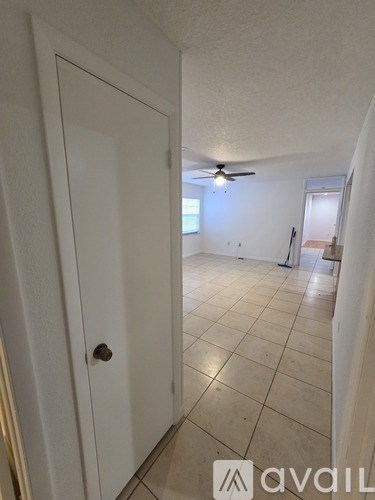 A room with a white door and a fan on the ceiling.