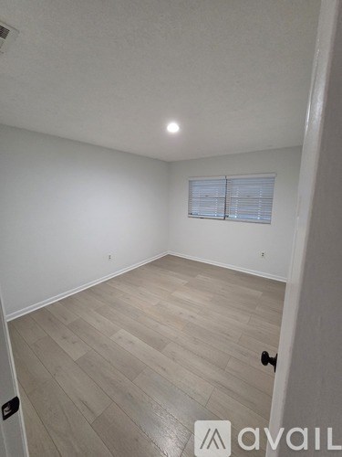 A room with wooden flooring and a window with blinds.