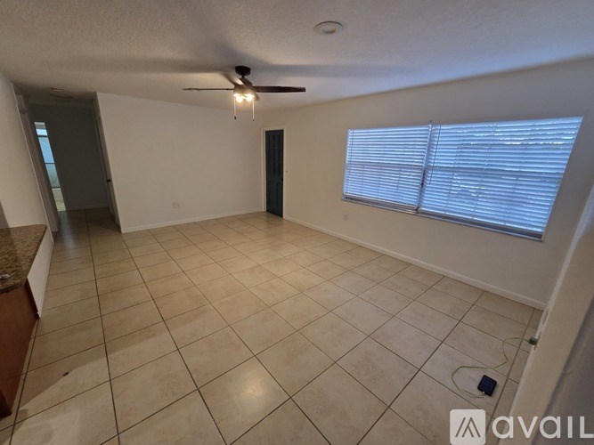 A spacious room with tiled flooring and a ceiling fan.