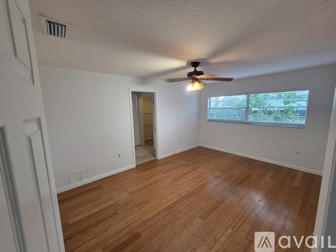 A room with a ceiling fan and wooden flooring.