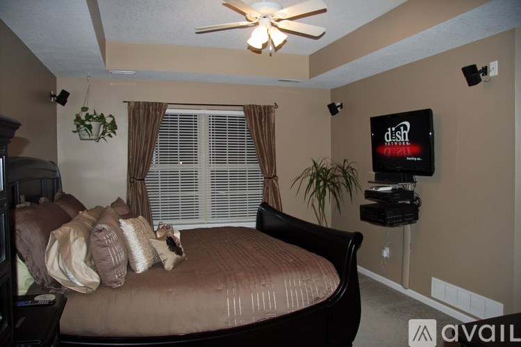 A bedroom with a bed, a ceiling fan, and a television.