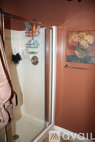 A bathroom with a glass shower door and a painting on the wall.